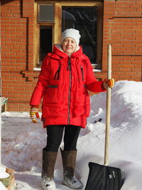 A woman with a shovel to clear snow near a private house. snow removal from the territory. 