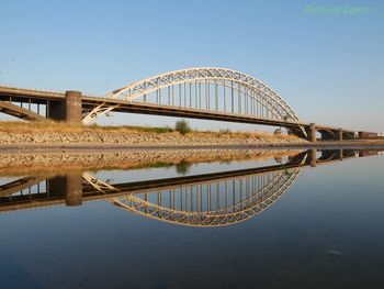 Arch bridge over river against sky