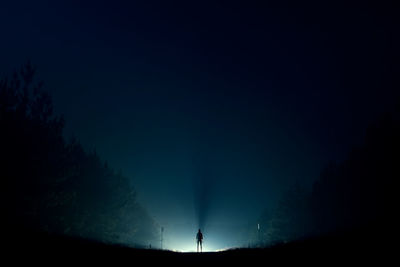 Silhouette man standing on land against sky at night