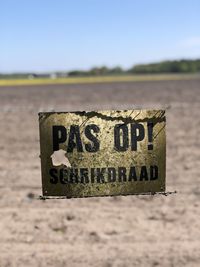 Close-up of information sign on field against clear sky