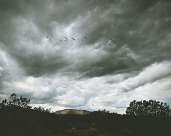 Silhouette landscape against cloudy sky