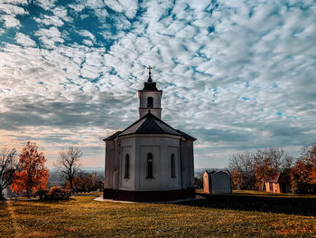 Church by building against sky during autumn