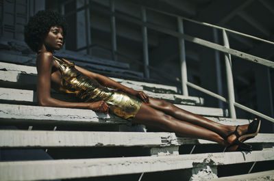 Low angle view of woman in dress looking away while sitting on steps