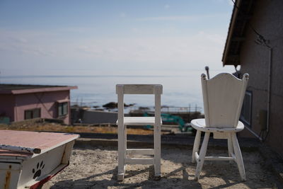 Chairs and table on beach by sea against sky