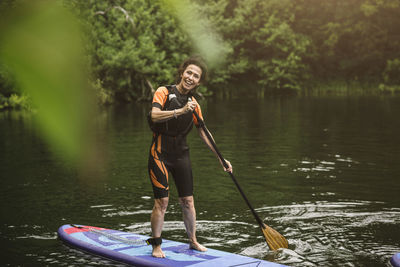 Portrait of smiling senior woman paddleboarding in sea during sup course