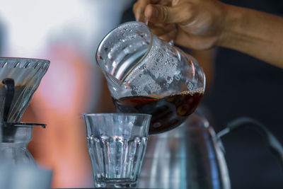 Close-up of hand pouring drink in glass