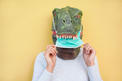 Woman wearing mask against yellow background