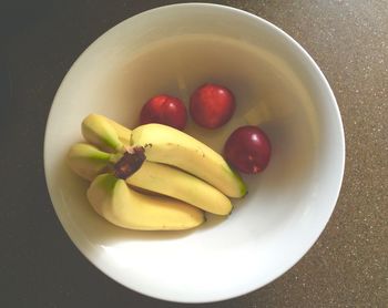 Directly above shot of bananas and plums in bowl on table