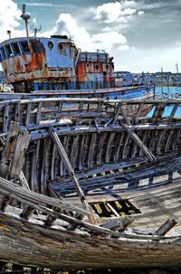 Abandoned boats moored at harbor against sky