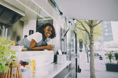 Portrait of smiling female owner standing in food truck