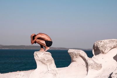 Rear view of man on beach against clear sky