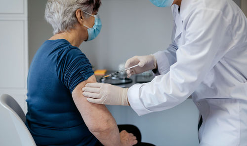 Midsection of doctor injecting patient in hospital