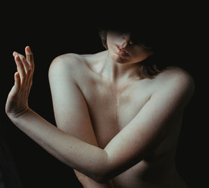 Side view of shirtless woman against black background