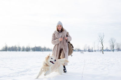 Young beautiful woman and her golden retriever dog having fun in winter.