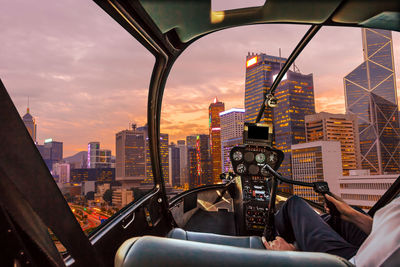 Illuminated cityscape against sky during sunset seen through helicopter