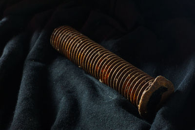 Close-up of rusty metallic bolt on black textile