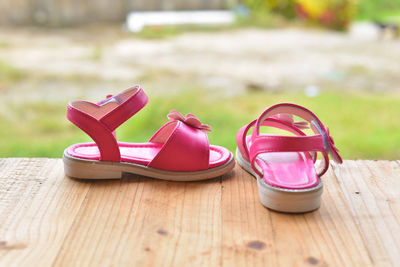 Close-up of pink sandals on wooden table