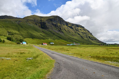 Scenic view of road amidst field against sky