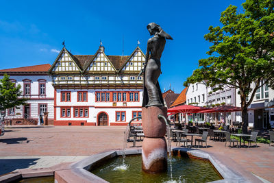 Statue by swimming pool against buildings in city