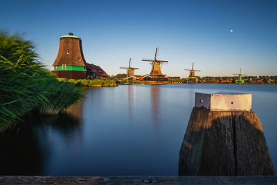 View of factory by lake against blue sky