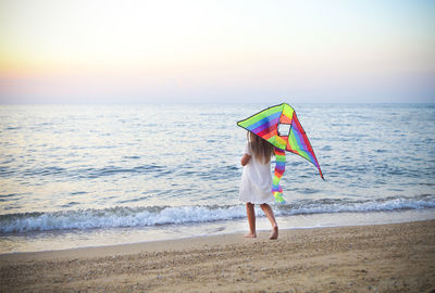 Full length of boy on beach against sky during sunset