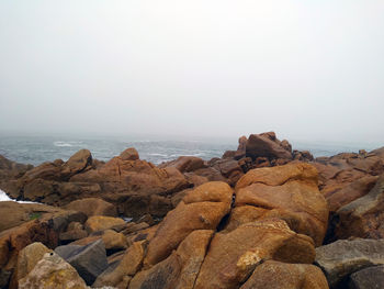 Rock formations on beach against clear sky