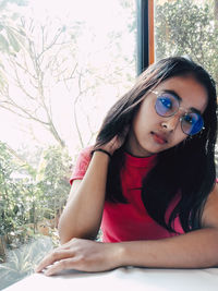 Portrait of young woman sitting on window