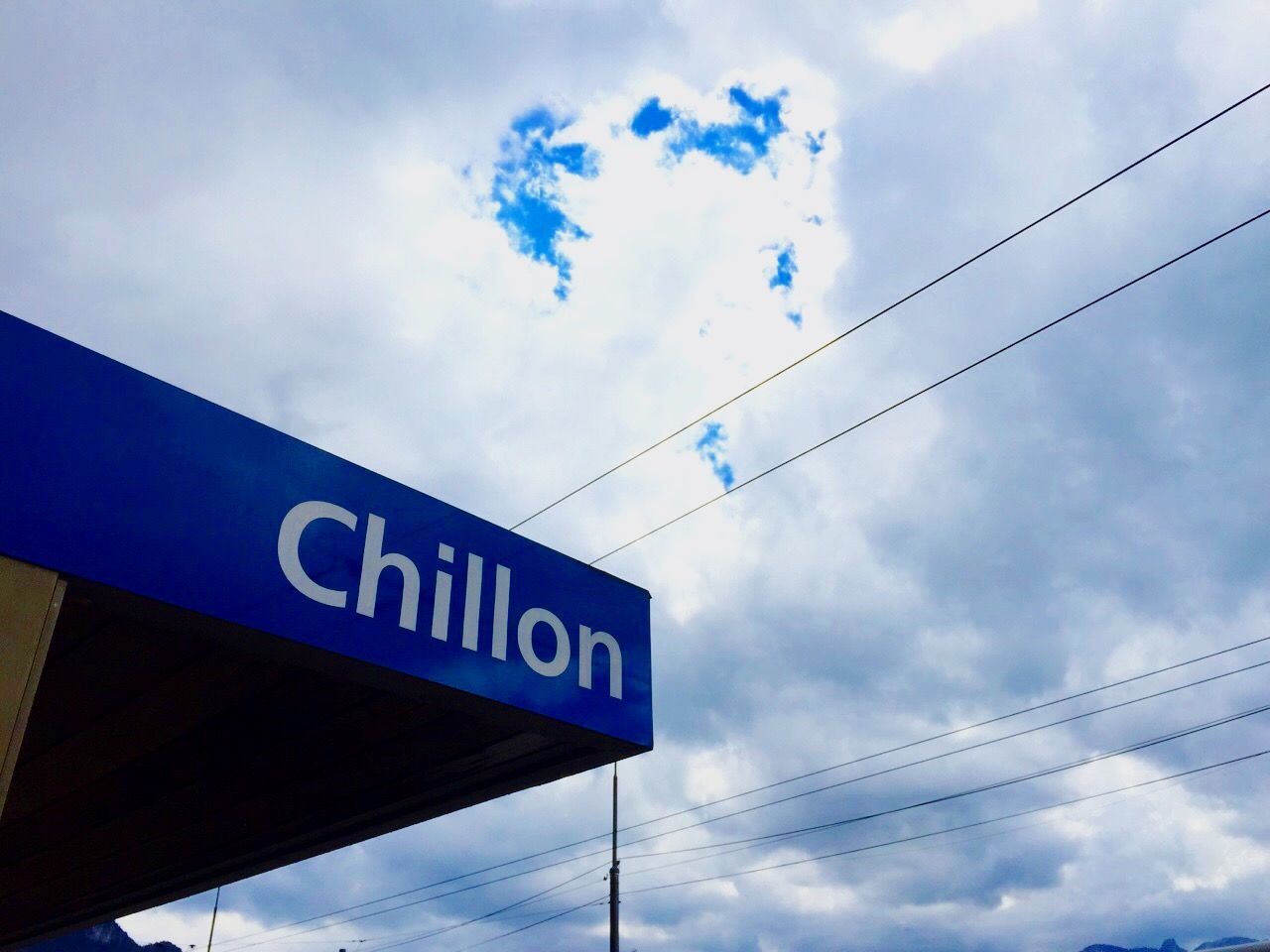 low angle view, sky, communication, power line, cable, text, western script, cloud - sky, connection, electricity, pole, guidance, blue, information sign, electricity pylon, cloudy, sign, cloud, power supply, road sign