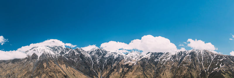 Panoramic view of snowcapped mountains against blue sky