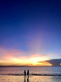 People on beach against sky during sunset