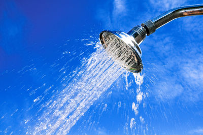 Close-up of shower splashing water against sky