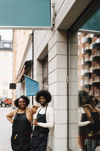 Smiling male and female barbers standing outside barber shop