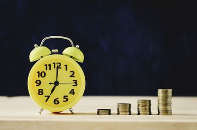 Close-up of alarm clock and stacked coins on table