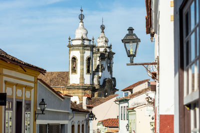 Low angle view of street light amidst buildings against sky