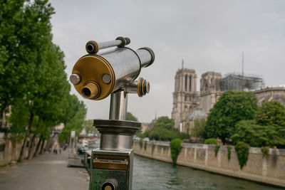 View of coin-operated binoculars by river in city