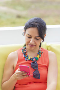Woman using phone while sitting on sofa