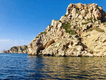 Rock formations in sea against clear blue sky