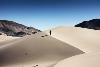 Scenic view of sand dune against clear blue sky