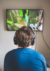 Rear view of boy using mobile phone at home