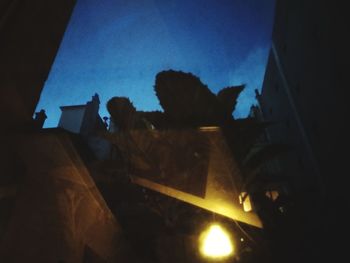 Low angle view of silhouette buildings against blue sky