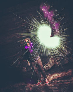 Man with firework display standing on rock at night