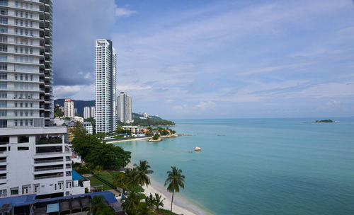 Buildings by sea against sky