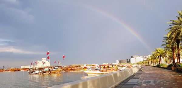 Rainbow over river in city against sky