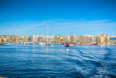 Buildings by sea against blue sky