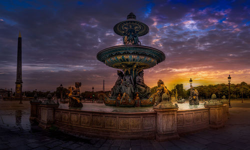 Statue of fountain in city at sunset