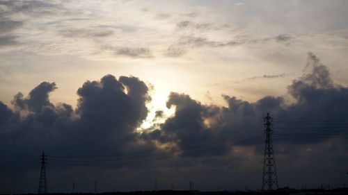 Low angle view of silhouette electricity pylon against sky