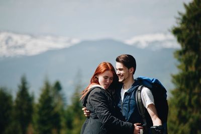 Cheerful couple embracing against mountain