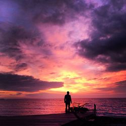 Silhouette of people on beach against cloudy sky