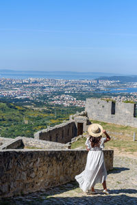 Young woman in white dress standing at klis fortress overlooking coastal city of split in croatia