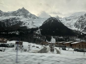 Scenic view of snow covered houses and mountains against sky